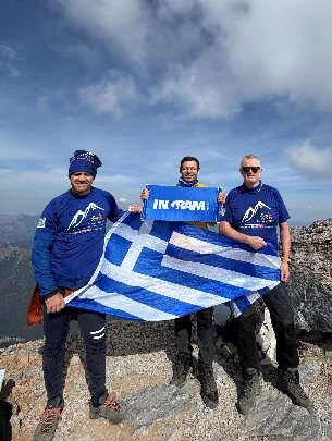 Climbers holding the Greek flag on the summit of Mytikas