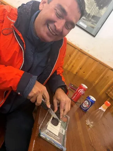 A climber smiling at a table inside the mountain refuge