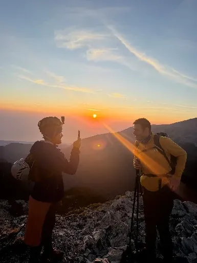 Two climbers watching the sunrise above the clouds on the ascent
