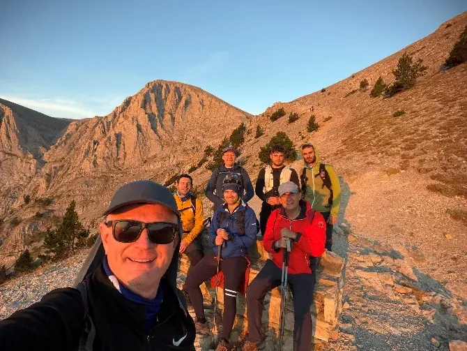 The team resting on a rocky ridge at sunrise, with the Olympus peaks behind